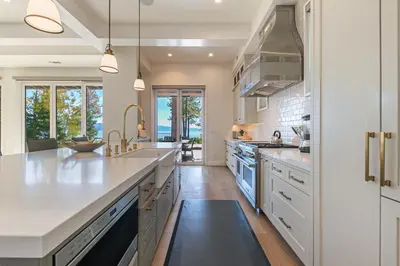 a large kitchen with white cabinets and a large island at Spellbound Lakefront Lodge by Tahoe Getaways - 5 BR w Hot Tub, Buoy & Beach access in Kings Beach