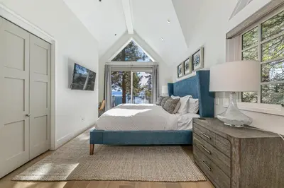 a bedroom with a bed and a table with a lamp at Spellbound Lakefront Lodge by Tahoe Getaways - 5 BR w Hot Tub, Buoy & Beach access in Kings Beach
