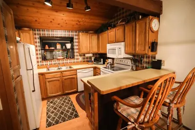 a kitchen with wooden cabinets and a white refrigerator at Updated Mammoth condo on Red line in Mammoth Lakes