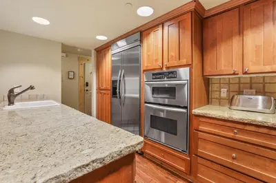 a kitchen with wooden cabinets and a stainless steel refrigerator at Grandeur at Elevation – 3 Bedroom Loft condo in Kirkwood
