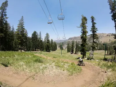 a person riding a bike on a dirt road under a ski lift at Grandeur at Elevation – 3 Bedroom Loft condo in Kirkwood