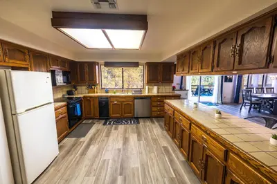 a kitchen with wooden cabinets and a white refrigerator at Sierra Vista Near Yosemite #Majestic Views# Tesla EV in Oakhurst