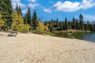 a bench sitting on a sandy beach next to a lake at Well Kept Condo CS#3 - Pets OK in Bear Valley