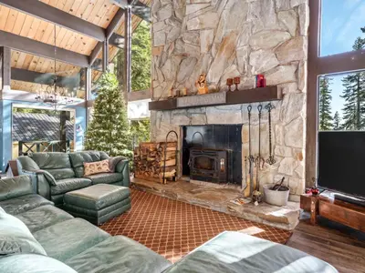 a living room with a stone fireplace and green furniture at Awesome Home Above the Lake - Dogs Welcome VH315 in Bear Valley