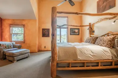 a bedroom with a wooden bed and a chair at XXL Snowcreek #747 - 5 Bedroom 4 Bathroom Sleeps 12 Pet Friendly, Amazing Mountain Views in Mammoth Lakes