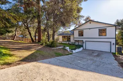 a white house with a garage on a dirt road at Sequoia's Dream with Mountain View, Spa, Heated Floor, Bar, Cinema! in Oakhurst