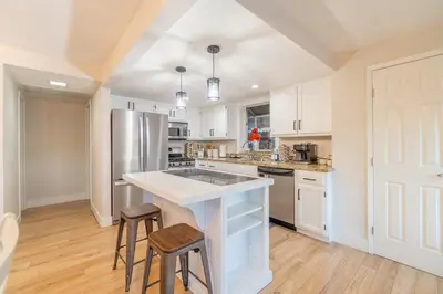 a kitchen with white cabinets and a kitchen island with stools at Modern 3-Bedroom Escape in Northwest Reno in Reno