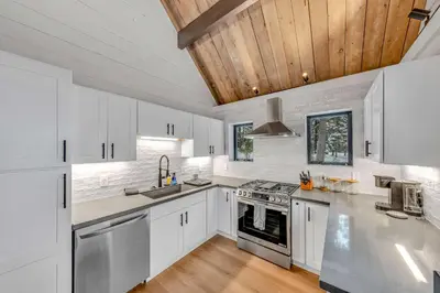 a kitchen with white cabinets and a wooden ceiling at Tahoe City Vacation Rental with Fireplace and Deck in Tahoe City