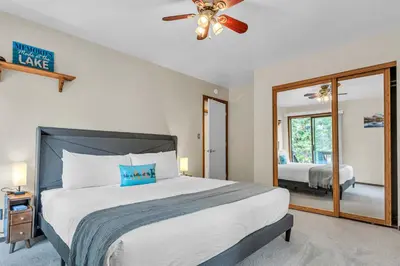 a bedroom with a bed with a ceiling fan and a mirror at Cozy Kings Beach Vacation Rental with Deck in Kings Beach