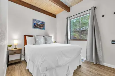 a white bedroom with a large bed and a window at Beautiful Homewood Retreat with Deck and Grill in Homewood