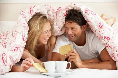 a man and a woman laying in bed eating food at Elliott House Boutique Inn in Shaver Lake