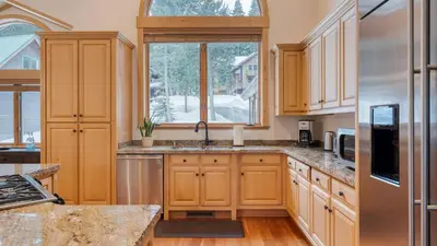 a kitchen with wooden cabinets and a window at 5 mins to Ski Resort Ping Pong Pool Table Deck Donner Ridge by AvantStay in Truckee