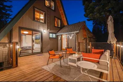 a house with a deck with chairs and a couch at Mountain Modern The Tahoe A-Frame w Private Pier in Homewood