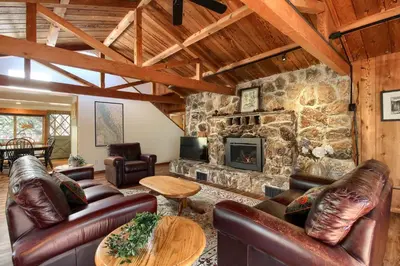 a living room with leather furniture and a stone fireplace at Tranquility House-Riverfront-Fireplace-Sleeps six in Oakhurst
