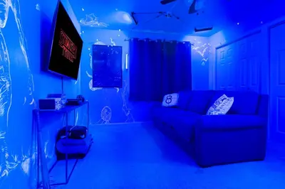 a blue living room with a couch and a tv at Immersive Stranger Things Experience in Clovis