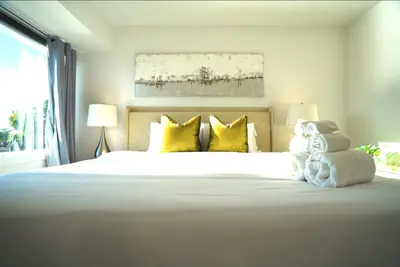 a bedroom with a large white bed with yellow pillows at Stunning Waterfront 3BR Retreat - Perfect Getaway in Discovery Bay