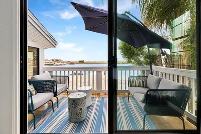 a patio with chairs and an umbrella on a balcony at Marlin Cove Pet Friendly Waterfront Retreat in Discovery Bay