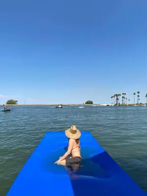 a woman in a hat sitting on a blue raft in the water at Marlin Cove Pet Friendly Waterfront Retreat in Discovery Bay