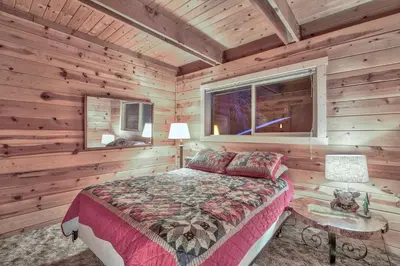 a bedroom with a bed and a window in a log cabin at Cholula Chalet 811C in South Lake Tahoe