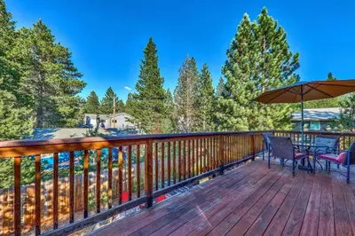 a deck with two chairs and an umbrella at Das Waldhaus 1973P in South Lake Tahoe