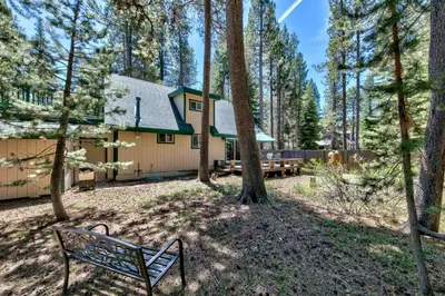 a house in the woods with a bench at 1207S Cabin in the Pines in South Lake Tahoe