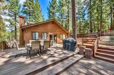 a cabin with a table and chairs on a wooden deck at 1760T Thunderbird Cabin in South Lake Tahoe