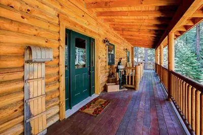 a front porch of a log cabin with a green door at Tahoe Moose Lodge 1170AC in South Lake Tahoe