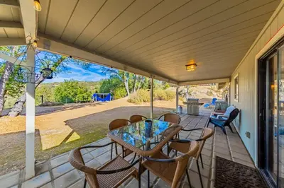 a porch with a glass table and chairs on it at Yosemite Wooded Hills, Pool Table, Fitness, Views in Oakhurst