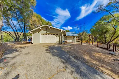 a house with a garage on a dirt road at Yosemite Wooded Hills, Pool Table, Fitness, Views in Oakhurst