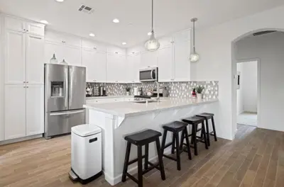 a kitchen with white cabinets and a counter with stools at Casita Tulare in Tulare