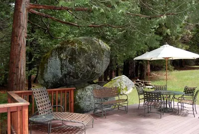 a deck with chairs and tables and an umbrella at 68 Wawona Dome View in North Wawona