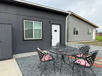 a glass table with four chairs and a table and a building at GUEST RANCH HOUSE w POOL access near NATL PARKS in Dinuba