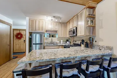 a kitchen with a marble counter top and wooden cabinets at The Cozy Condo in Kingswood Estates