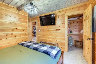 a bedroom with wooden walls and a flat screen tv at Walk to Golf, Lake Twain Harte Cabin with Fireplace in Twain Harte
