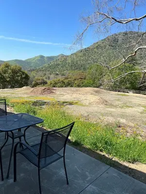 a table and chairs on a patio with a view of a field at Brand New Scenic Sequoia House in Three Rivers