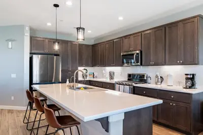 a kitchen with wooden cabinets and a white counter top at Spacious 4BR Home With BBQ, Near Sequoia & Fresno in Hanford
