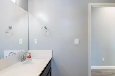 a white bathroom with a sink and a mirror at Spacious 4BR Home With BBQ, Near Sequoia & Fresno in Hanford