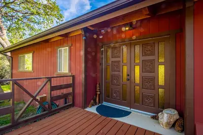 a house with a deck with a pair of doors at 10-acre Forest Villa, Single Floor, Hot tub, Patio in Oakhurst