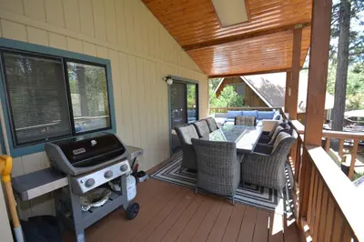 a screened in porch with a grill and a table and chairs at SunRidge at Willow Cove Free Night Special in Bass Lake