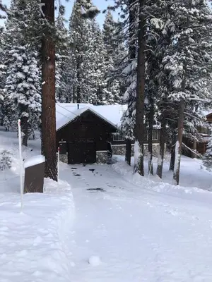 a snow covered yard with a cabin in the background at Cozy 3 bedroom home in Tahoe Donner in Truckee
