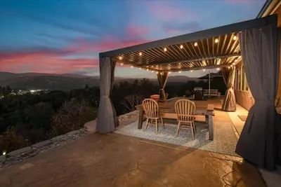 a patio with a table and chairs under a pergola at Hilltop Paradise with stunning views/hot tub/firepit/dog friendly in Oakhurst