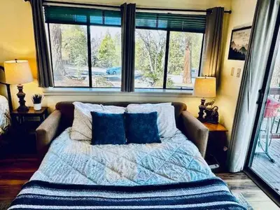 a bedroom with a bed with blue pillows and a window at Inside Yosemite Park-Cozy Corner Unit-Sleeps 2 in Yosemite West