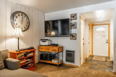 a living room with a clock and a tv on the wall at Sunshine Village #108- 1 +Loft , Sleeps 6. Steps from Free Town Shuttle ,Dog Friendly in Mammoth Lakes