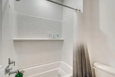 a white bathroom with a tub and a toilet at 15 Mi to Dtwn Sacramento Newly Built Home! in Sacramento
