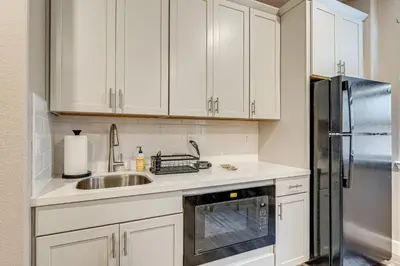 a kitchen with white cabinets and a sink and a refrigerator at 7 Mi to Folsom Lake Sacramento Area Apartment in Folsom