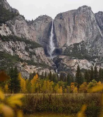 a waterfall on the side of a mountain with trees at Cozy Yosemite Cabin with Hot Tub in the Pines in Fish Camp