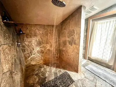 a bathroom with a shower with a stone wall at Cozy Yosemite Cabin with Hot Tub in the Pines in Fish Camp