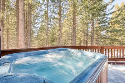 a hot tub on a deck with trees in the background at Venture in Tahoe Donner by Tahoe Getaways - 4 BR W Hot Tub, Pool Table, Great for Kids! in Truckee