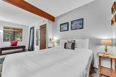 a bedroom with a large white bed and a chair at Kings Beach Cabin Private Hot Tub, Near Lake & Ski in Kings Beach