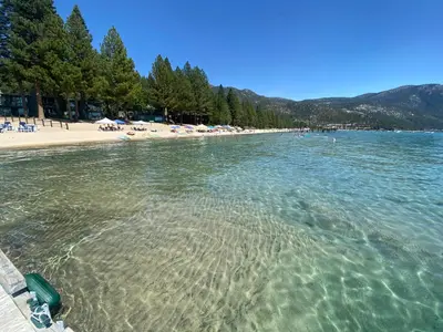a beach with chairs and umbrellas in the water at Experience the Beauty of Tahoe from Your Zephyr Cove Retreat! #2 in Zephyr Cove